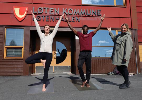 To i yogastilling og ei som peker på Løtenhallen